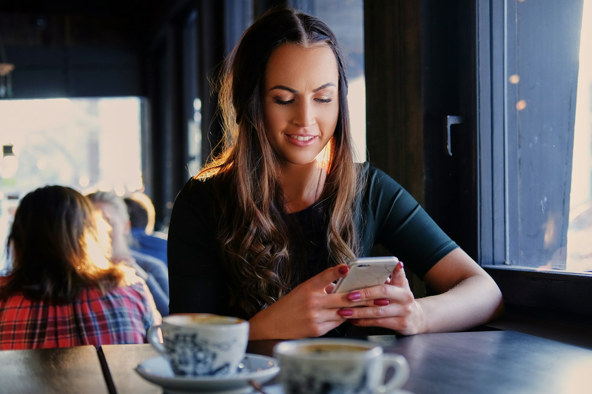 A woman texting an SMS in a cafe.